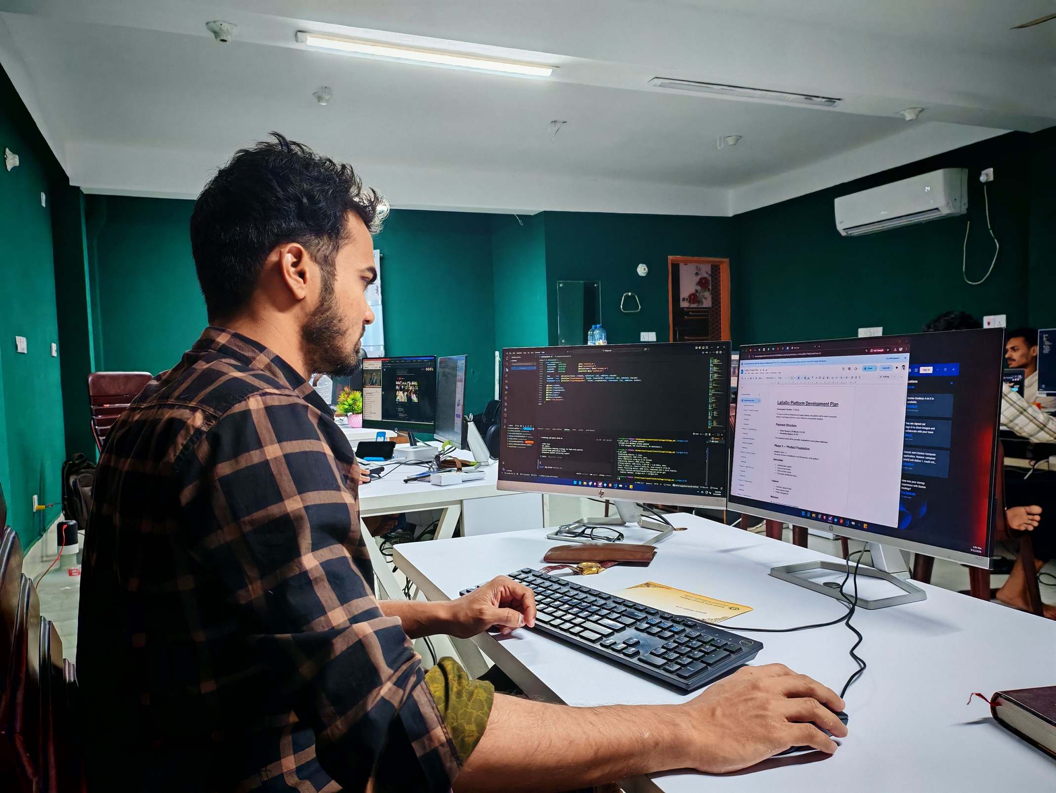 Software developer workspace with monitors in an office, focused and engaged.